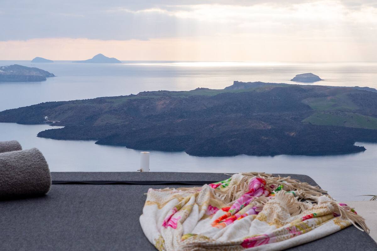 A view from a balcony with a blanket and towels on a chair, overlooking a body of water and islands.