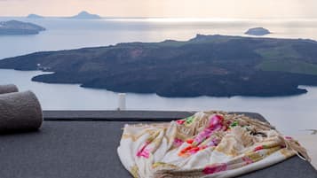 A view from a balcony with a blanket and towels on a chair, overlooking a body of water and islands.