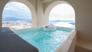 A hot tub with a view of the sea and a cityscape. - Caldera Cliff Illusion (Santorini)