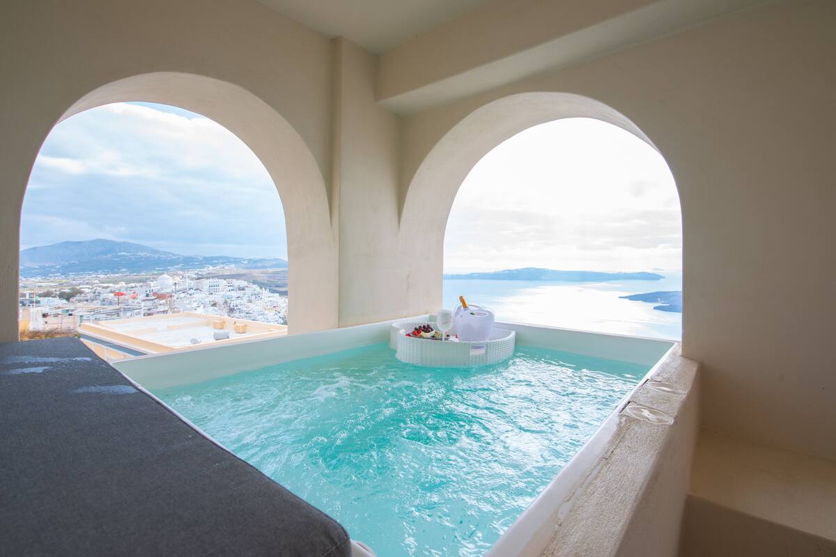 A hot tub with a view of the sea and a cityscape.