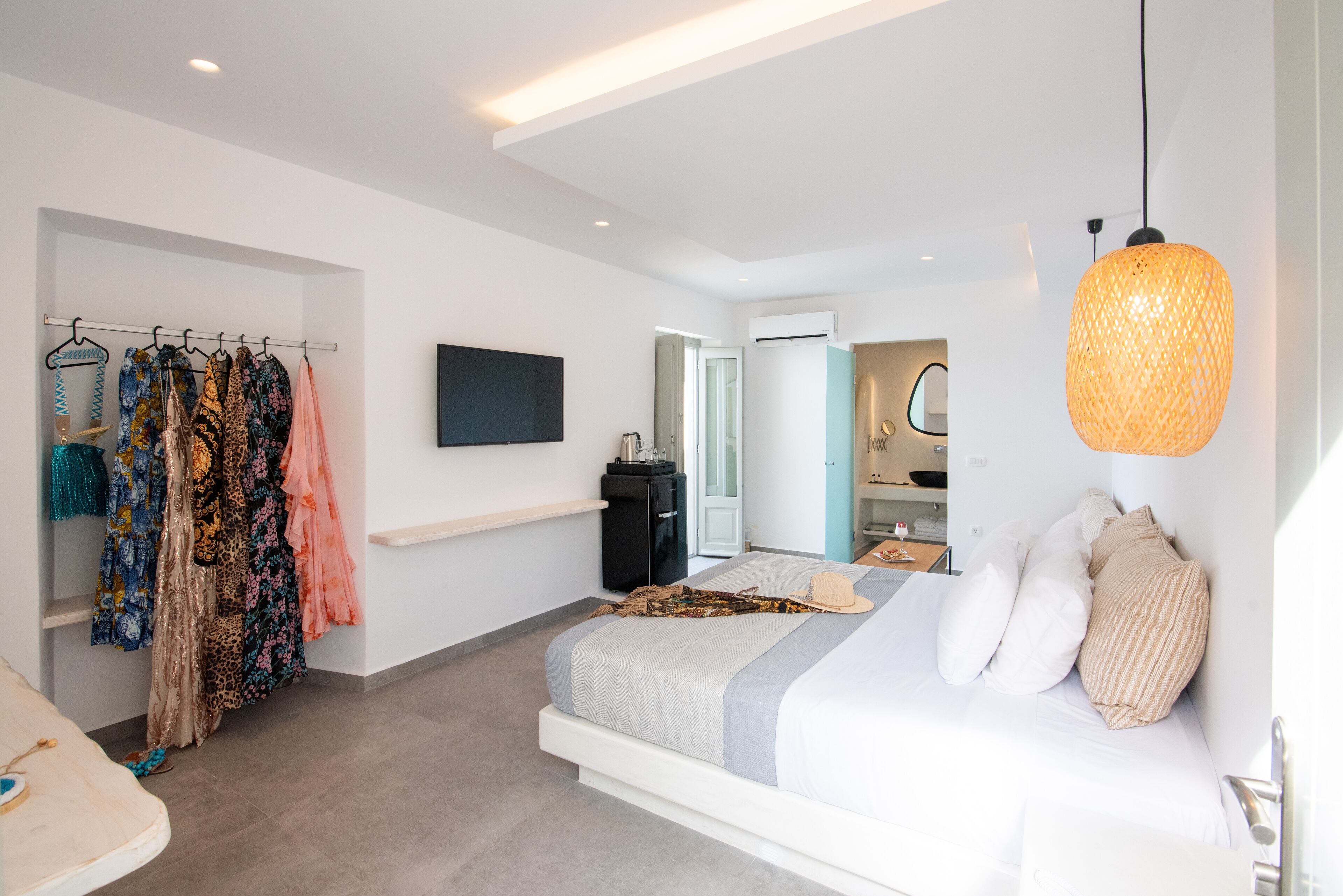A modern bedroom with a bed, a wardrobe, a television, and a hanging light fixture.