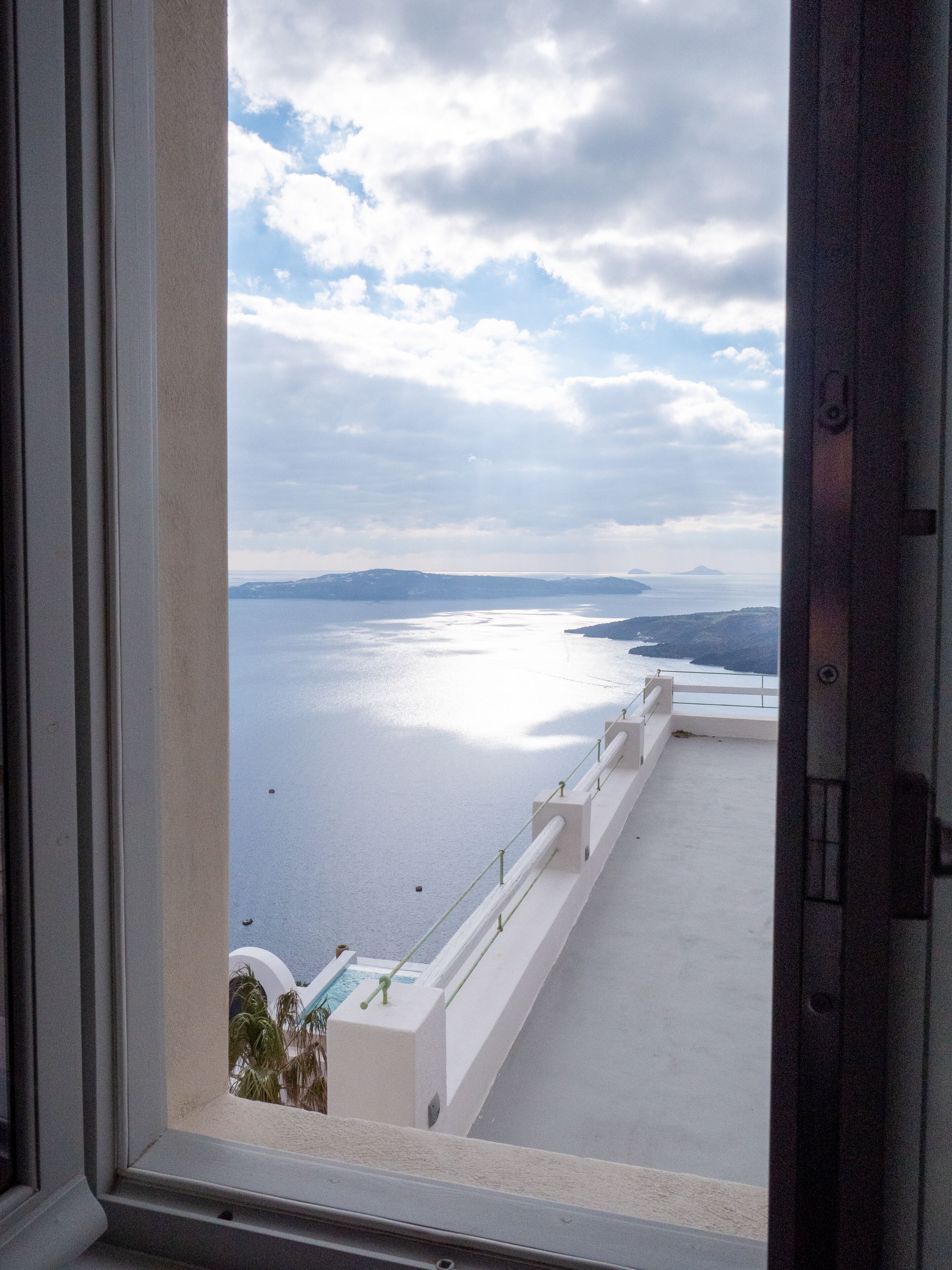 A balcony with a view of a body of water and distant landforms.
