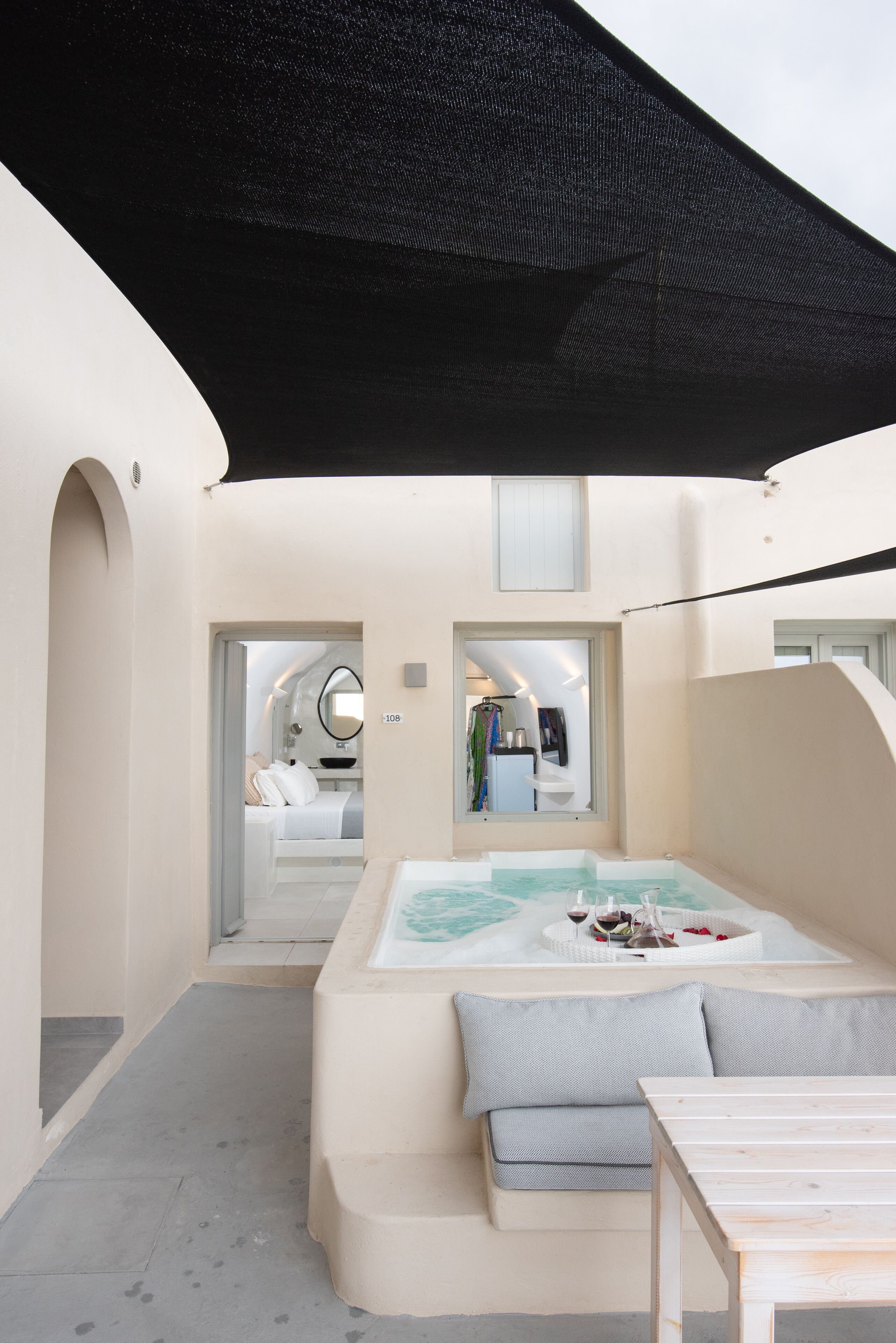A spa area with a hot tub, seating, and a view into a bedroom.