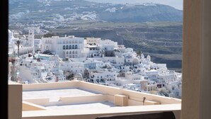 A view of a coastal town with white buildings, a wooden deck, and a clear sky. - Caldera Cliff Illusion (Santorini)