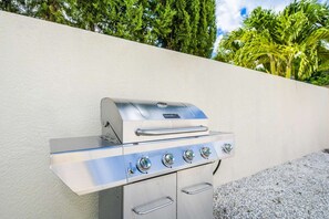 Una parrilla de acero inoxidable para exteriores con cuatro quemadores, fijada a una pared.