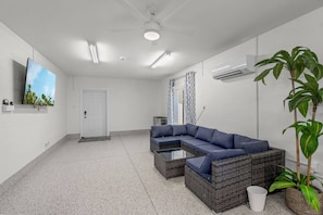 Ein modernes Wohnzimmer mit einem Ecksofa, einem Couchtisch und einem an der Wand montierten Fernseher.