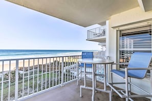 Enjoy the ocean view from this balcony with a table and chairs.