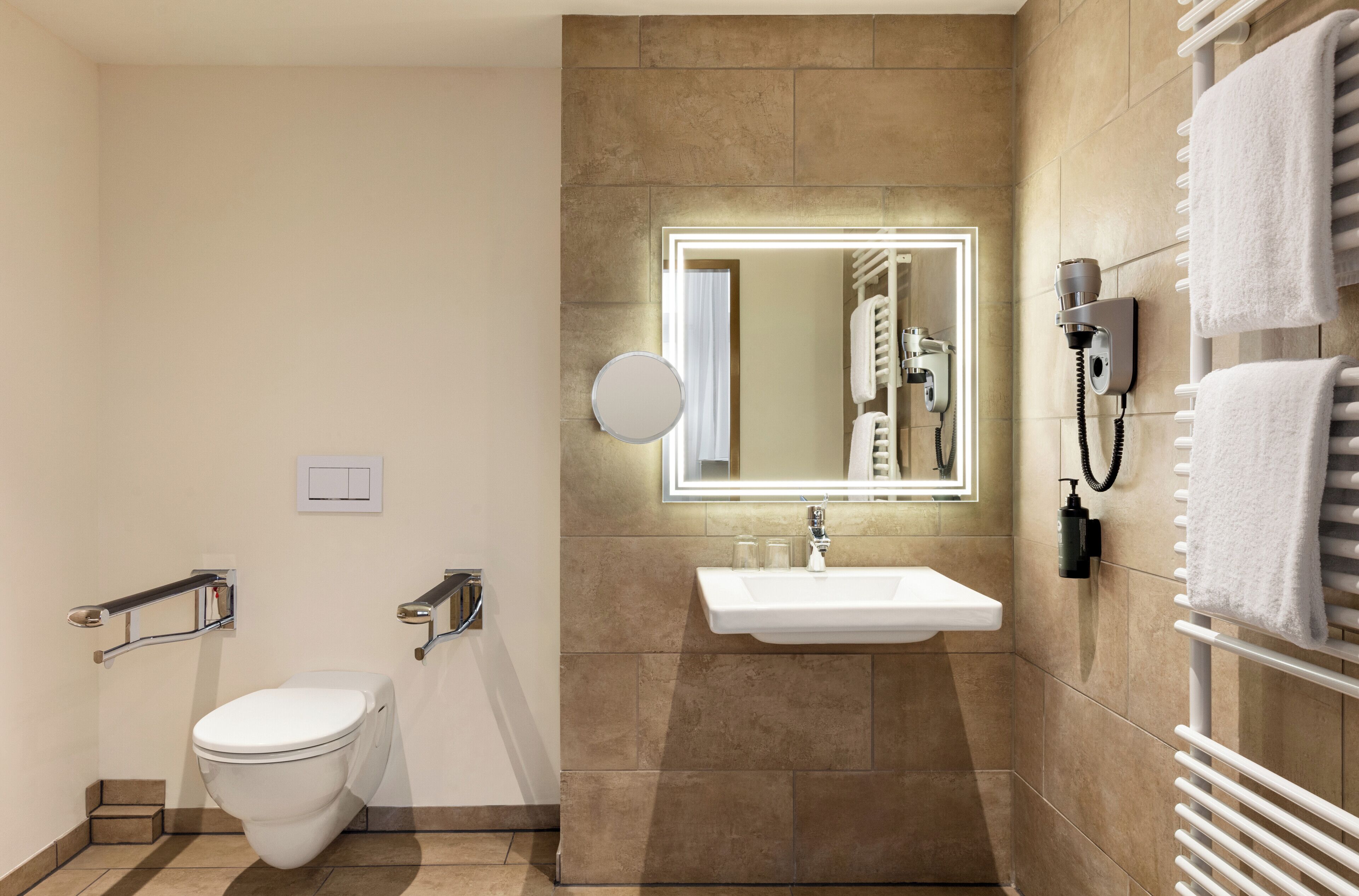 Un baño moderno con inodoro, lavabo y perchero para toallas.