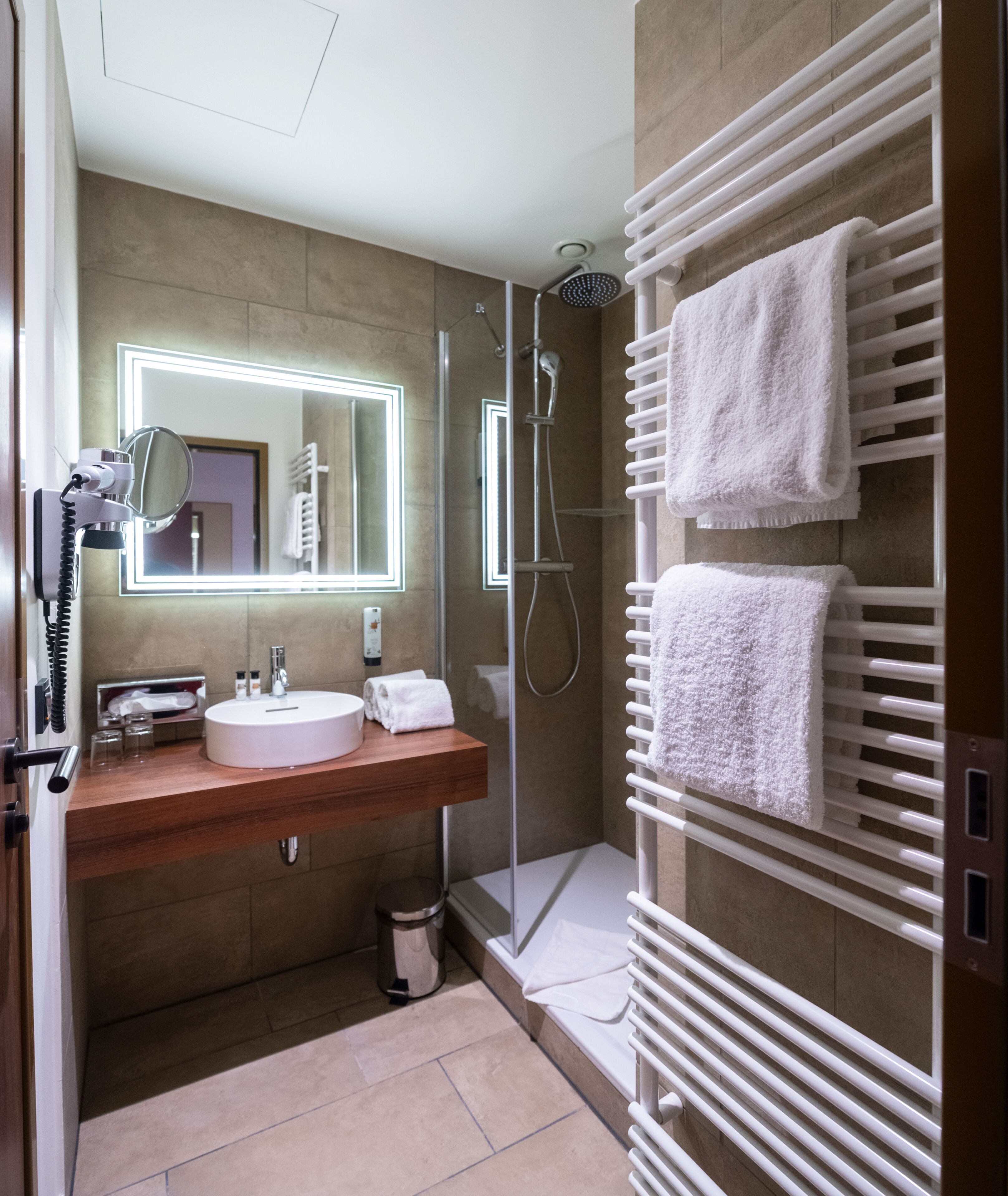 Un baño moderno con ducha de vidrio, tocador con espejo y barra para toallas.