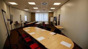 A conference room with a long table, multiple chairs, and a whiteboard.
