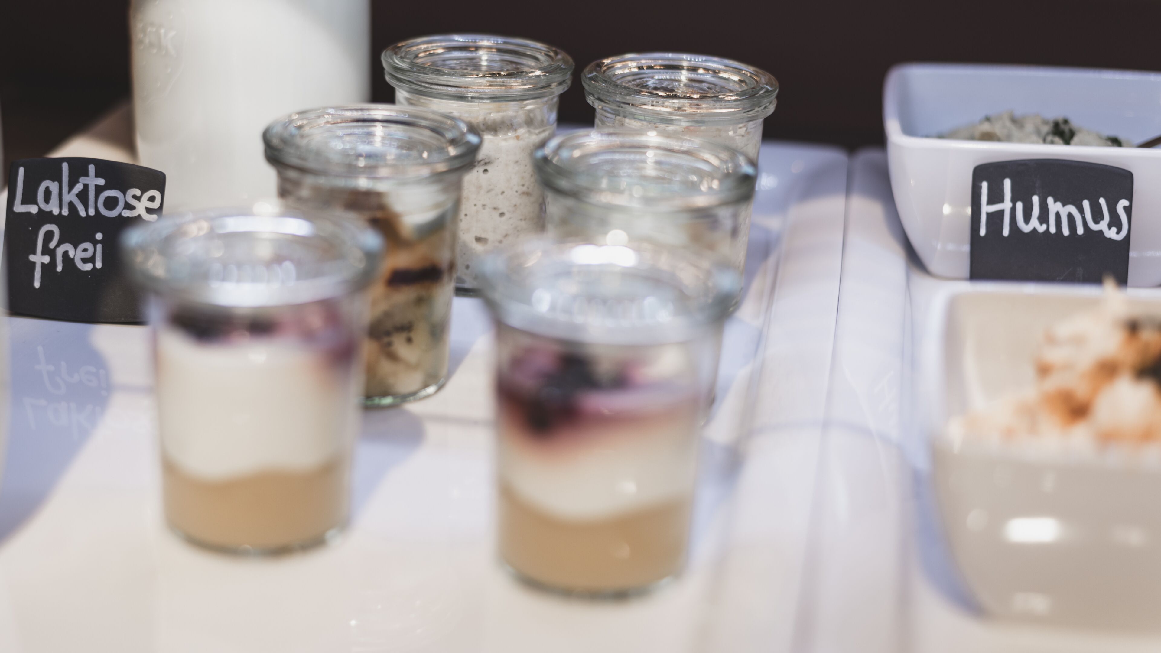 A table with small glass containers of layered desserts, each labeled with a name.