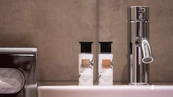 Un baño con un grifo moderno y dos botellas de loción y acondicionador corporales The Perfumer's Garden.