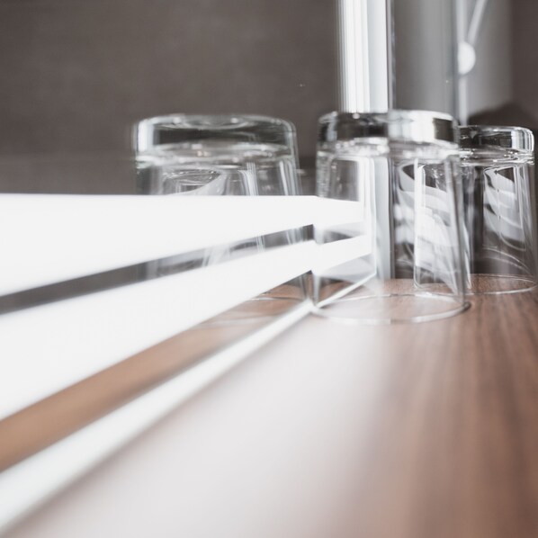 A series of clear glass tumblers on a wooden surface, likely a bar area.