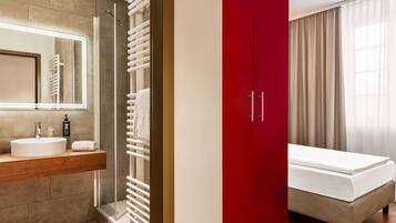 A modern bathroom with a large mirror, a sink, and a shower.