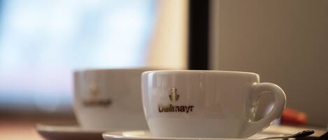 Deux tasses blanches, portant l’inscription « Dallinayr », sont posées sur une soucoupe, elle-même placée sur une table.