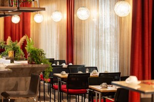 A restaurant with tables and chairs, red curtains, and hanging lights.