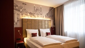 A hotel room with a large bed, a small bedside table, a wall-mounted lamp, and a window with curtains. - Hotel Postgalerie Speyer (Speyer)