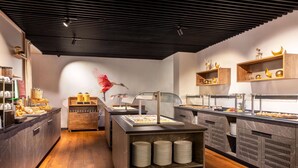 A buffet area with various food stations, wooden shelves with decorative items, and a central serving counter. - Hotel Postgalerie Speyer (Speyer)