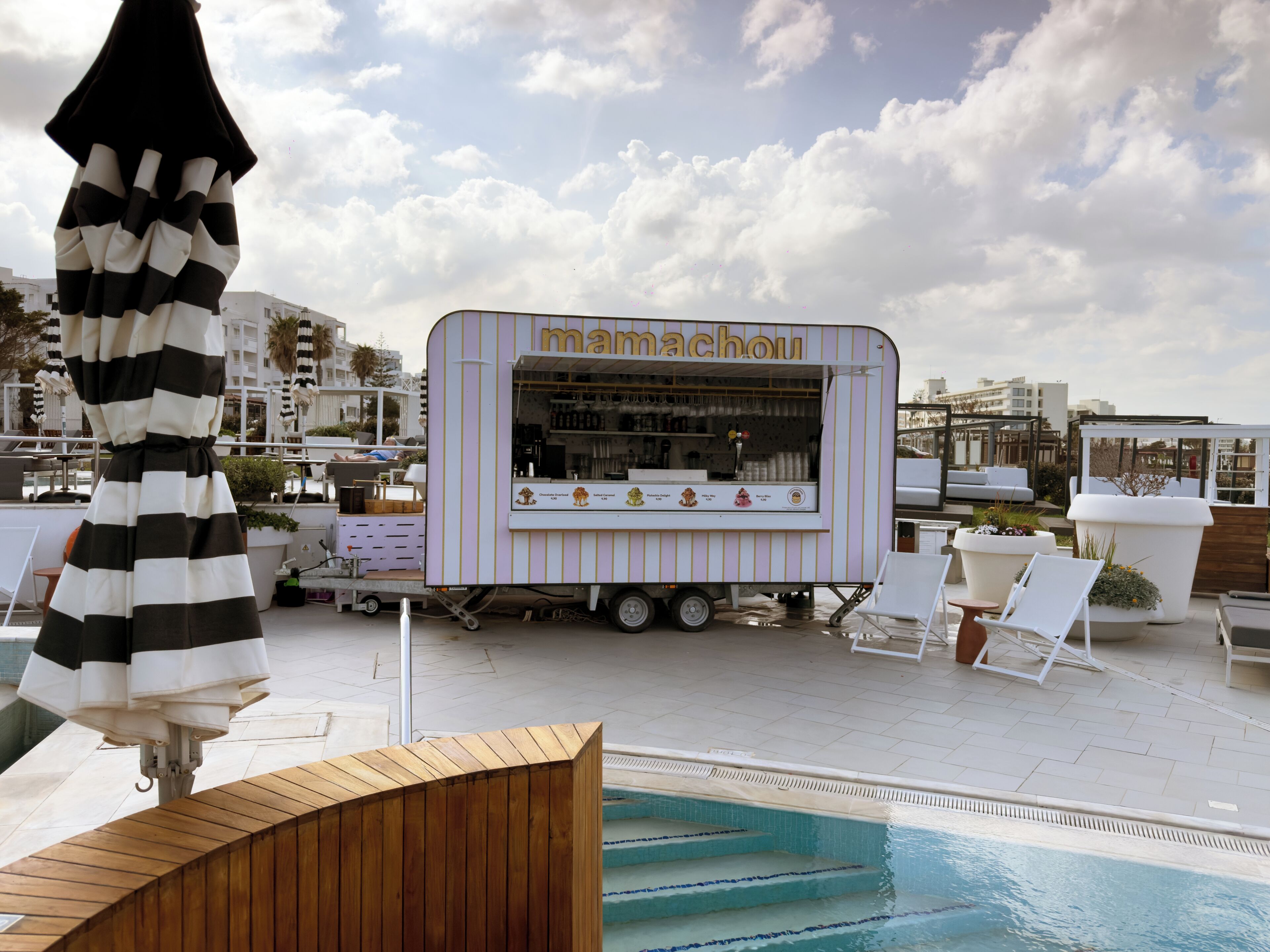 Un espace aménagé au bord de la piscine, comprenant un camion-restaurant baptisé « mamancho », des chaises longues et une piscine.