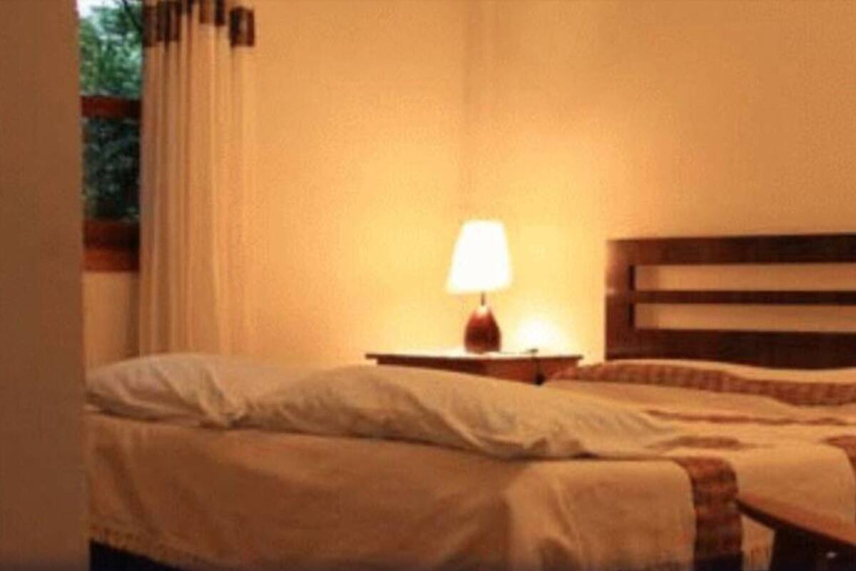 Un dormitori amb un llit, una tauleta de nit i una làmpada.