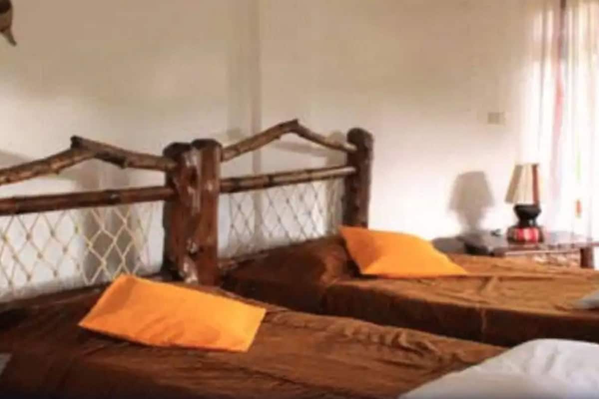 Habitació amb dos llits, cadascun amb capçal de fusta i almoades taronges.