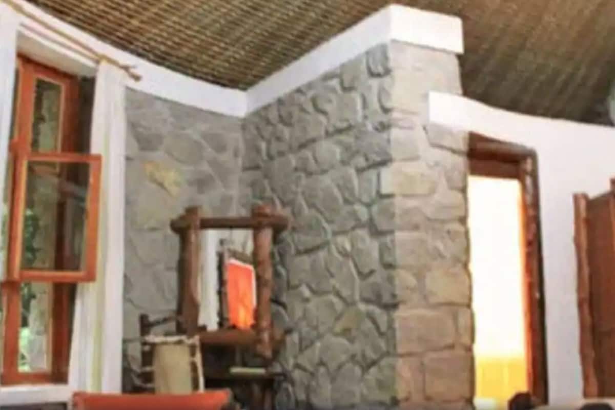 Habitació amb parets de pedra, una porta de fusta, una finestra amb marc vermell i un armari de fusta.