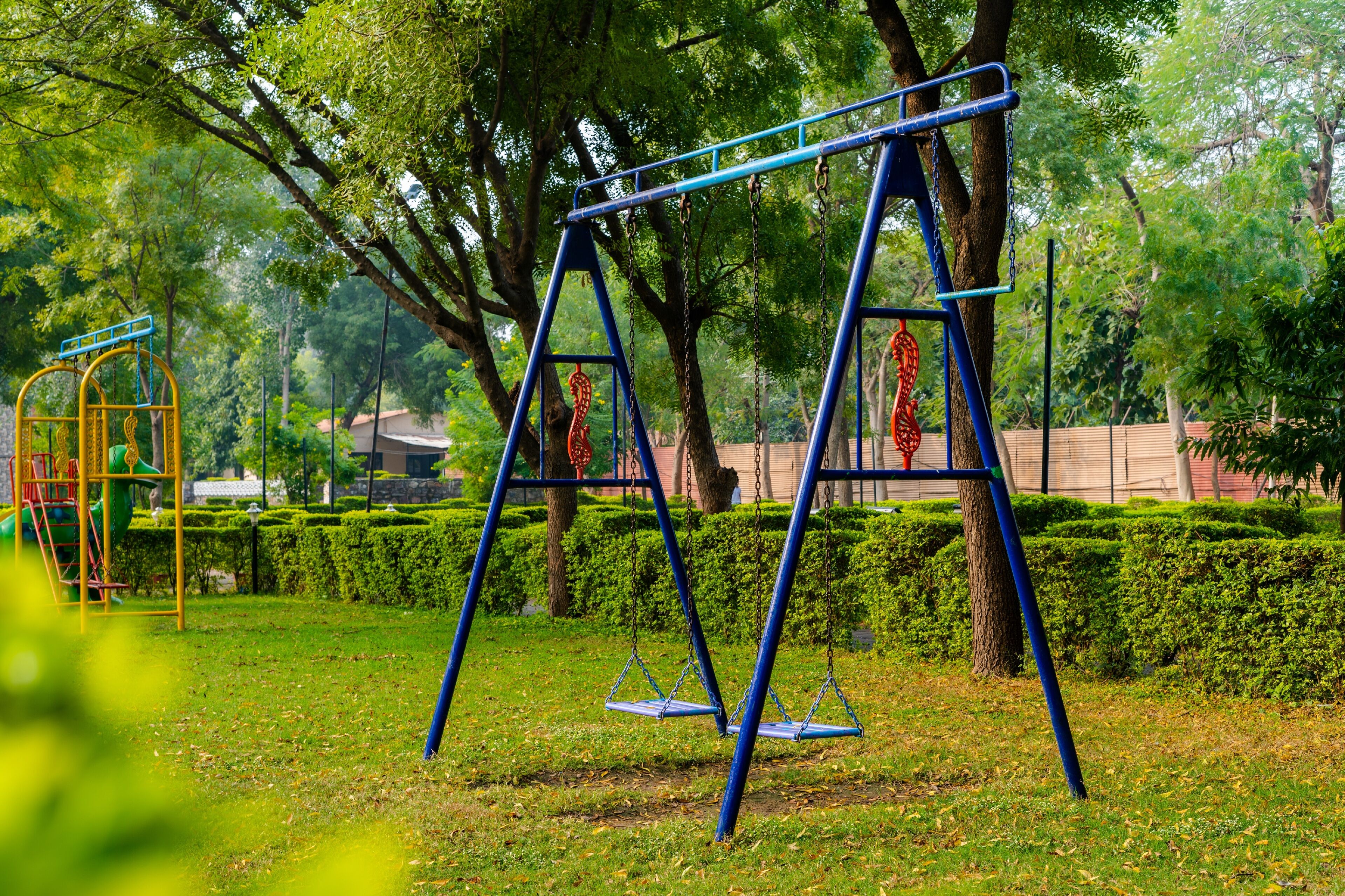 A park with blue swing sets and a playground.