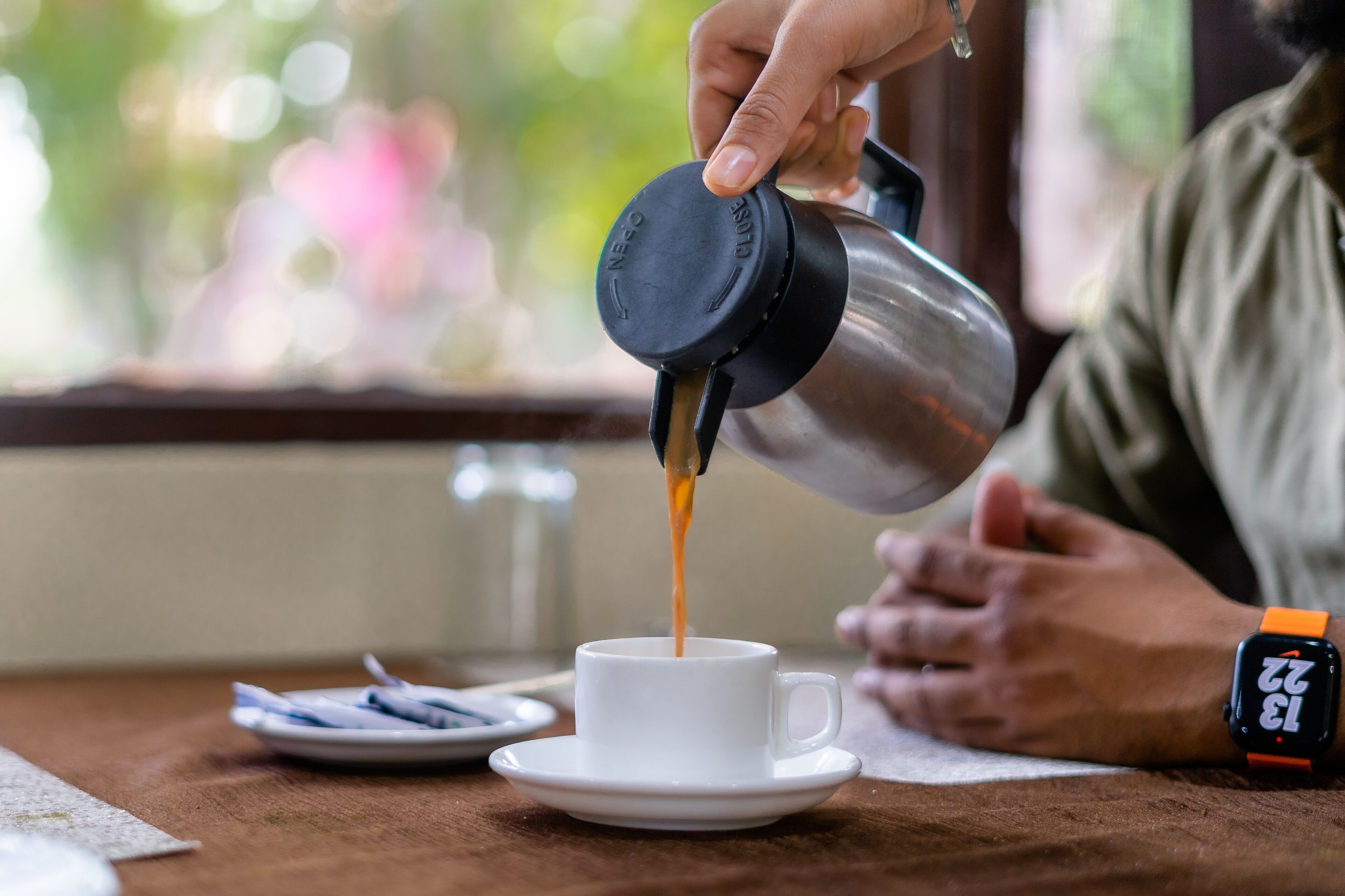 A person pouring coffee into a cup on a table.