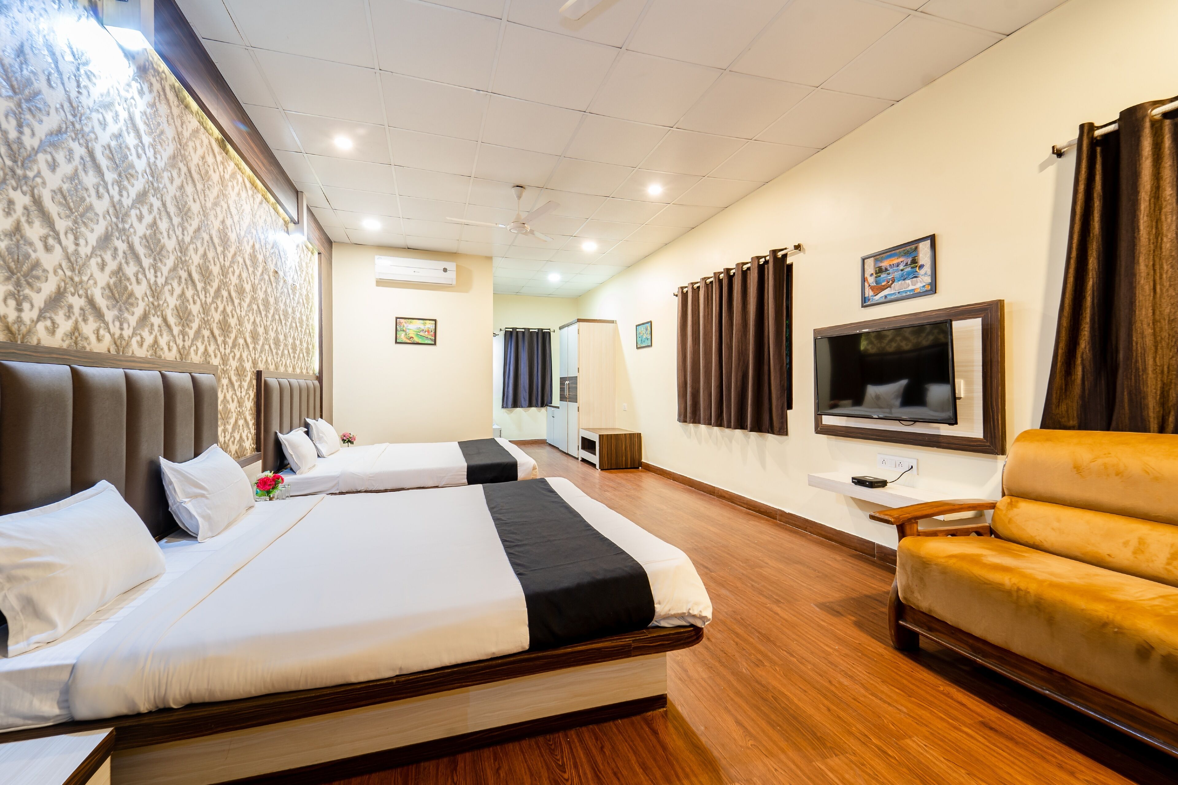 Habitación de hotel con dos camas, un sofá, un televisor y un ventilador de techo.
