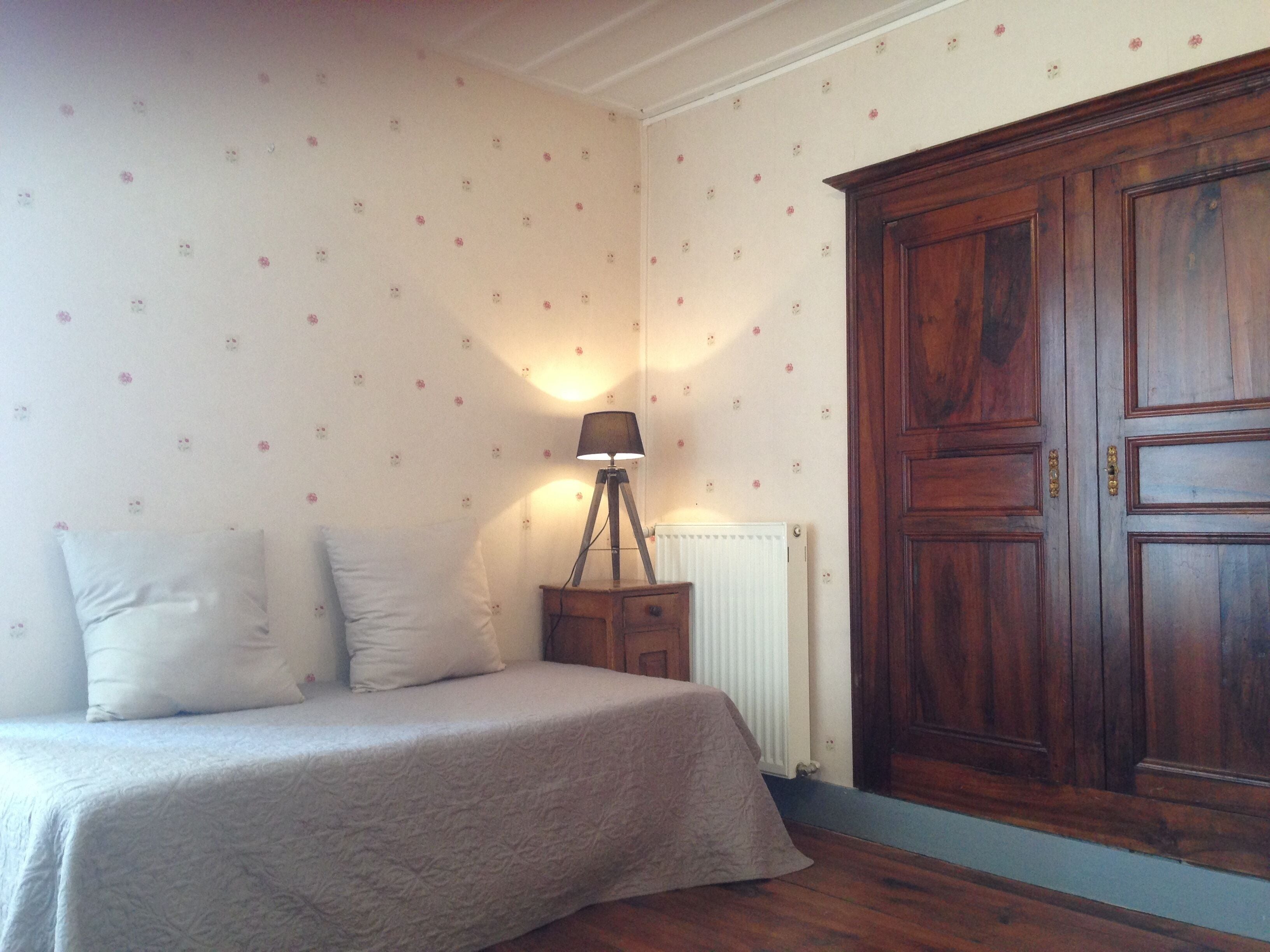 Une chambre à coucher avec un lit, une table de chevet, une lampe et une armoire.