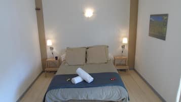 A bedroom with a bed, two bedside lamps, a wall-mounted light, and a painting.