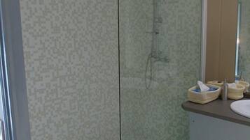 A glass-enclosed shower with a handheld showerhead and a wall-mounted faucet.