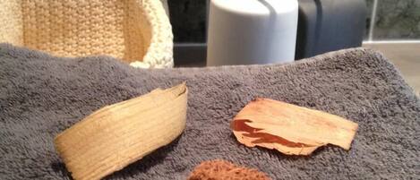 Un baño con una toalla gris, un objeto de madera y una esponja marrón encima.
