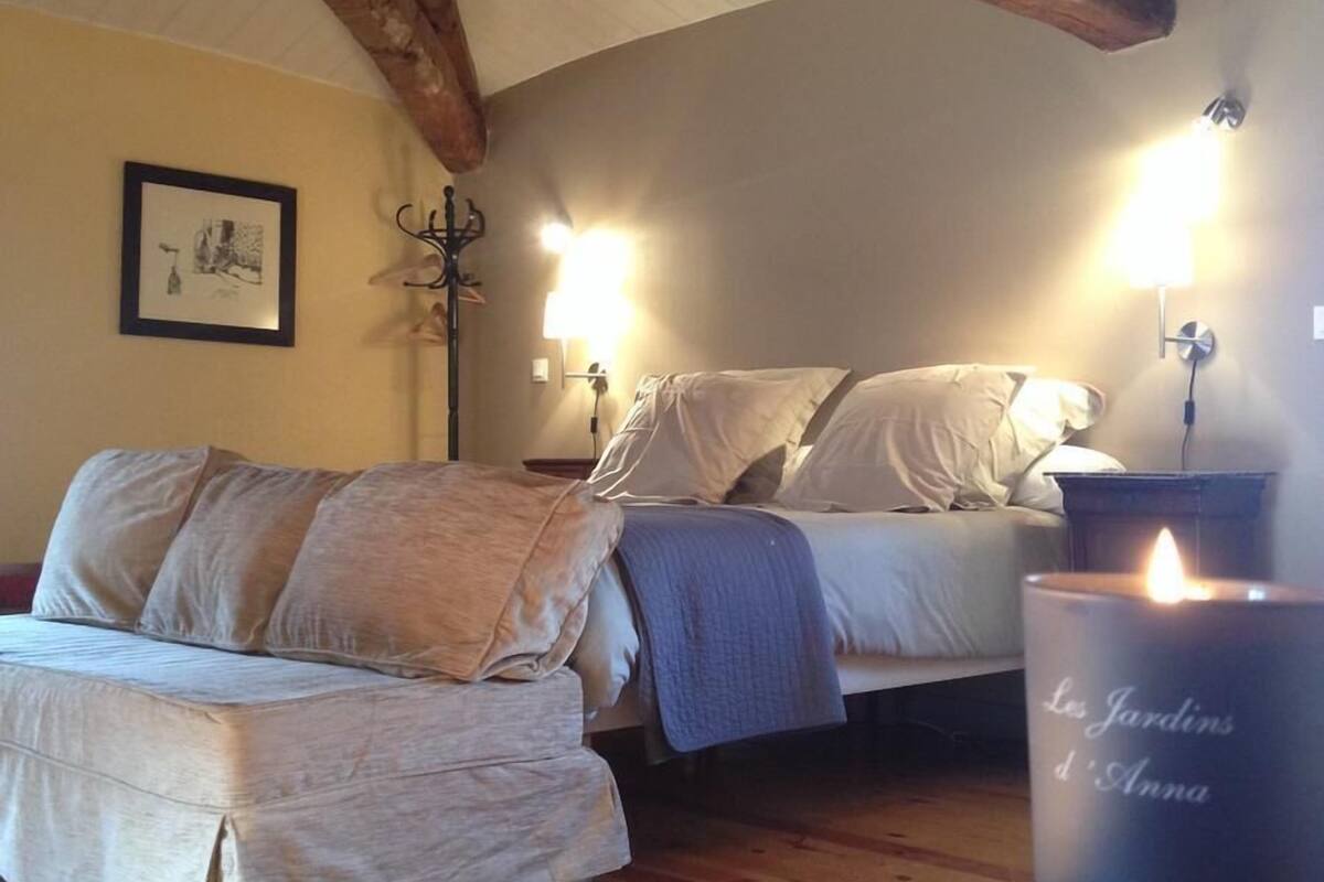 A cozy bedroom with a bed, a sofa, and a lit candle on a table.
