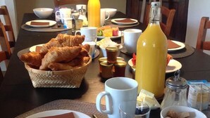 Una mesa de desayuno con cruasanes, zumo de naranja, café y diversas opciones para el desayuno.