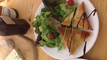 Une assiette avec une salade, un morceau de fromage et une bouteille de vinaigrette.