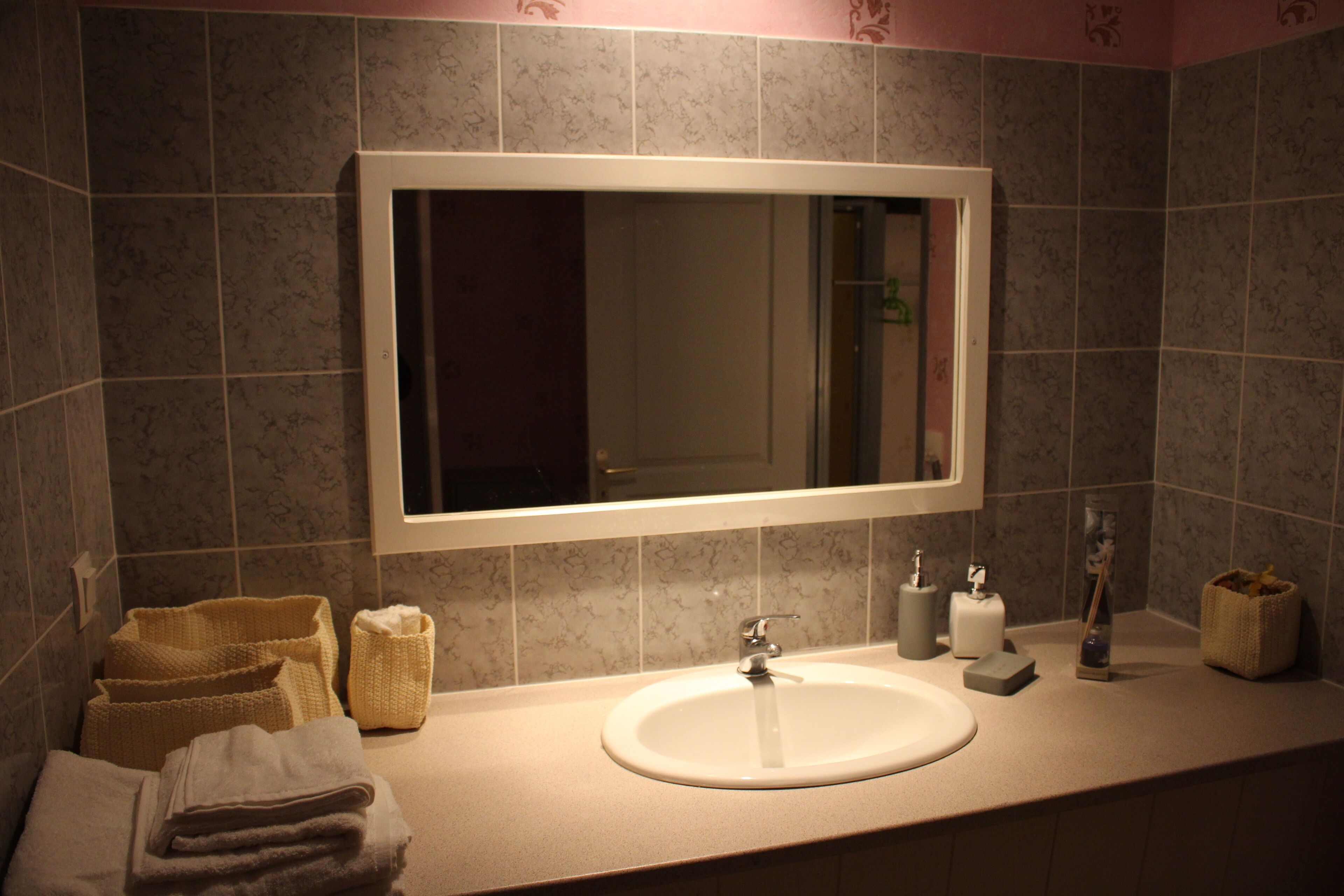 A bathroom with a large mirror, a sink, and a towel rack.