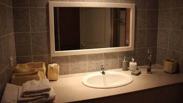 A bathroom with a large mirror, a sink, and a towel rack.