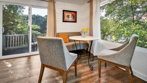 Une pièce comprenant deux fauteuils gris à revêtement en tissu, une petite table ronde, un coussin blanc et un tableau encadré accroché au mur.