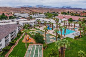 Un resort con varias edificaciones, un área de piscina central y una cancha deportiva.