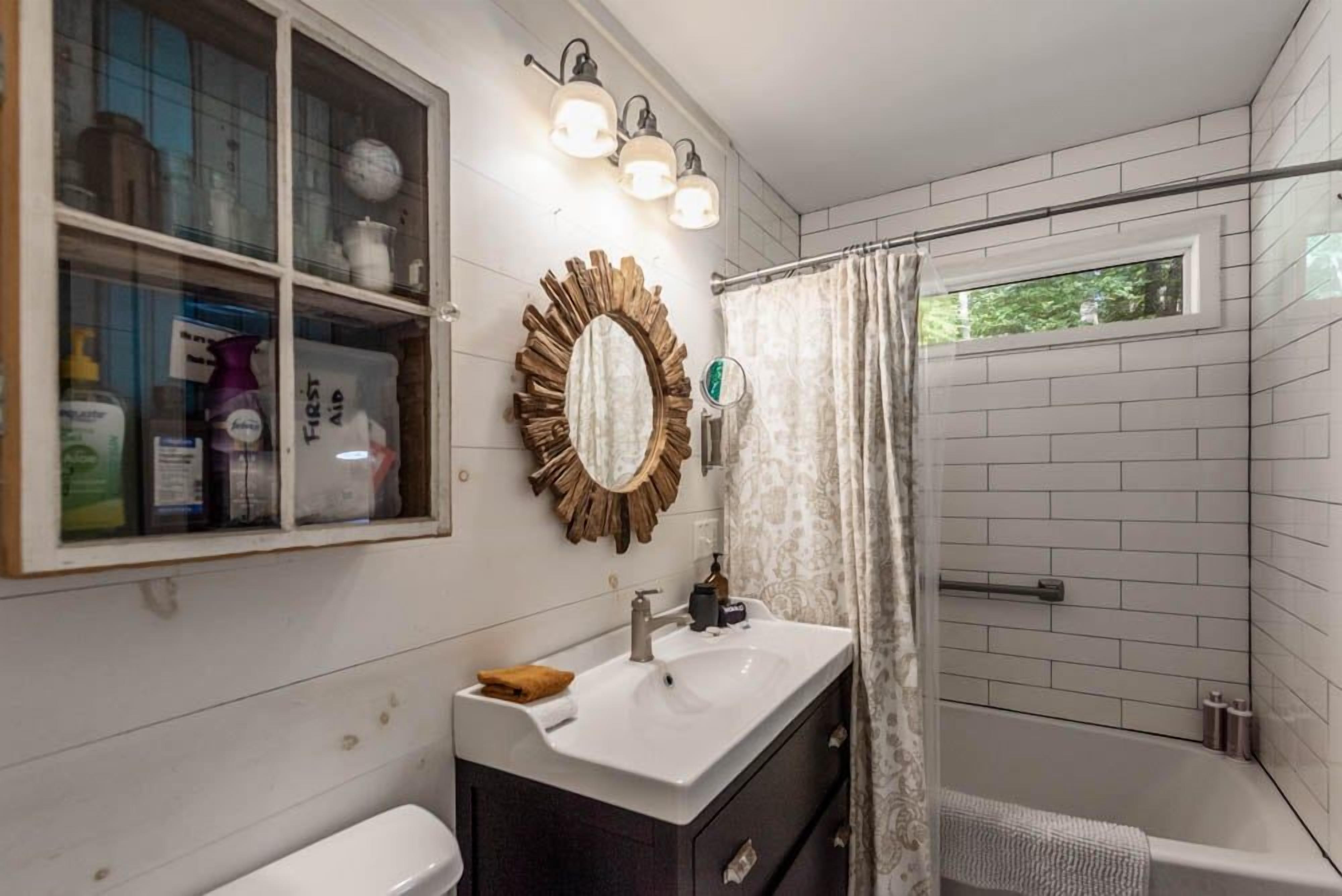 A bathroom with a white sink, dark cabinet, and a shower with a curtain.