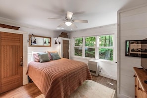 Quarto com cama, ventilador de teto, janela e cómoda.