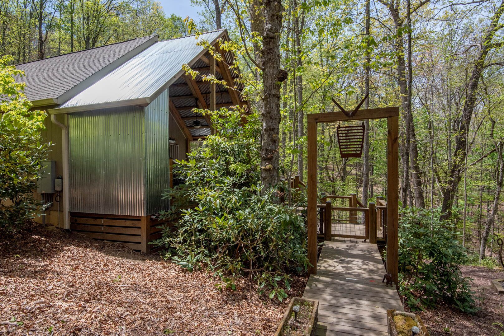 A rustic cabin with a metal roof, surrounded by dense forest.