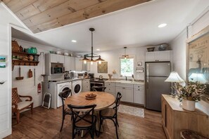 A modern kitchen with white cabinets, a central island, and a dining area with chairs.