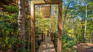 A wooden pathway leading through a forested area with a wooden archway overhead.