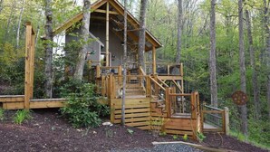 A wooden cabin with a steep staircase, surrounded by trees.