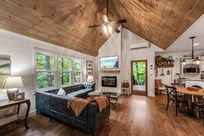 Uma sala de estar ampla com um sofá grande, lareira e área de jantar com móveis de madeira.