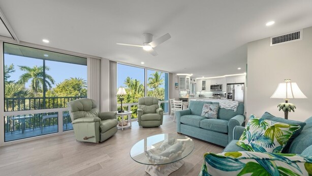 A spacious living area with a balcony, a kitchen, and a dining area. - Island Beach Club 330B – Gulf view vacation rental condo on Sanibel Island (Sanibel)