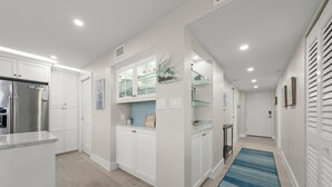 A modern kitchen with white cabinetry, a stainless steel refrigerator, and a glass-fronted display cabinet. - Island Beach Club 330B – Gulf view vacation rental condo on Sanibel Island (Sanibel)