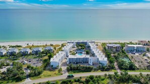 An aerial view of a resort with multiple buildings, a swimming pool, and a beach in the background. - Island Beach Club 330B – Gulf view vacation rental condo on Sanibel Island (Sanibel)